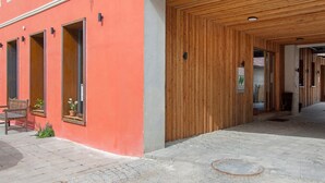 A building with a wooden entrance, a red exterior wall, and a paved walkway.