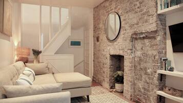 A living room with a sofa, a fireplace, a mirror, and a staircase.