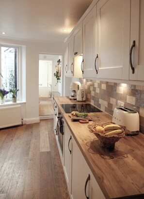 Eine moderne Küche mit weißen Schränken, einer Holz Arbeitsplatte, einem Toaster und einer Bananenkiste.