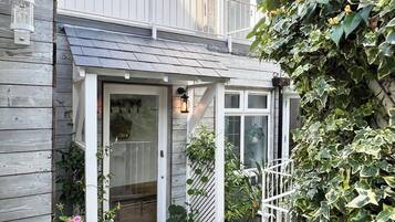 A residential property with a covered entryway, a brick pathway, and potted plants.