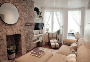 Ein Wohnzimmer mit Kamin, Fernseher, Sofa und Couchtisch.