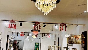 A spacious interior with a large chandelier, hanging decorations, and a display of antique furniture. - Hotel The Amaresh (Panipat)