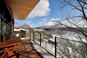 Eine Holzterrasse mit Blick auf eine verschneite Landschaft und Berge.