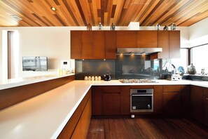 Eine moderne Küche mit Holzschränken, einem eingebauten Ofen und einem großen Fenster.