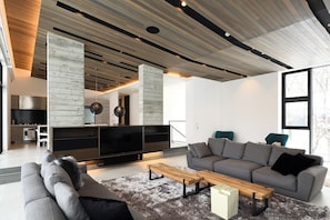 Ein modernes Wohnzimmer mit einem grauen Sofa, einem Holztisch und einem großen Flachbildfernseher.