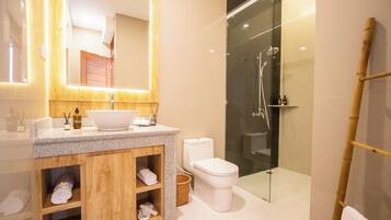 Un baño moderno con encimera de granito, mueble de tocador de madera, inodoro blanco y cabina de ducha con mampara de vidrio.