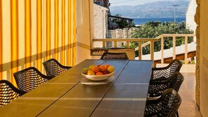 Een balkon met een tafel, stoelen en een schaal fruit.