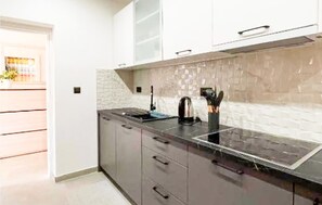 Eine moderne Küche mit schwarzem Arbeitsplatz, weißer Spritzschutzwand und dunklen Schränken.