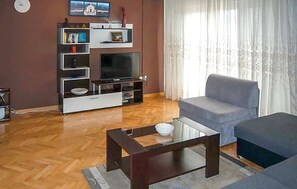 A living room with a flat-screen TV, a grey sofa, a glass coffee table, and a wooden floor. - 4 bedroom amazing apartment in Supetar (Supetar)