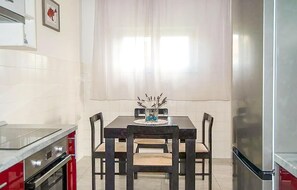 A kitchen with a dining table, chairs, a vase with dried plants, and a refrigerator. - 4 bedroom amazing apartment in Supetar (Supetar)