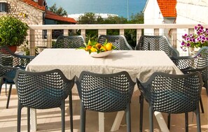 A table set with chairs, a bowl of fruit, and a view of the sea. - 4 bedroom amazing apartment in Supetar (Supetar)