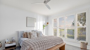 Ein Schlafzimmer mit einem Bett, Nachttisch, Lampe und Deckenventilator.