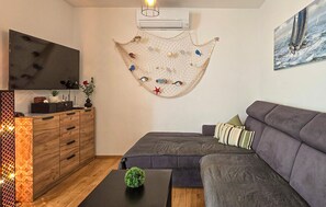 Ein Wohnzimmer mit einer Couch, einem Fernseher, einem Holzschrank und einer Wanddekoration.