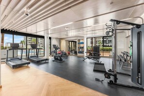 Ein modernes Fitnessstudio mit Laufbändern, Kraftgeräten und einem großen Spiegel.