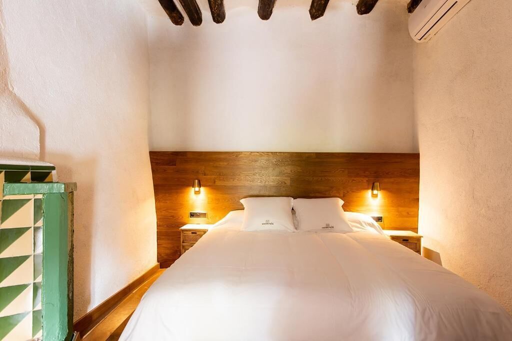 A bedroom with a wooden headboard, two bedside lamps, and a green door.