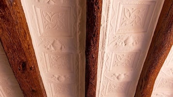 A close-up of a ceiling with intricate embossed patterns and wooden beams.