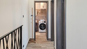 A narrow hallway leading to a laundry area with a washing machine and a wooden wall. - 2 bedroom stunning home in Selca (Selca)