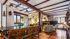 Un interior rústico con vigas de madera a la vista, un banco de madera, un sofá estampado y una pared de piedra.