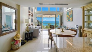 Un interior moderno con comedor, cocina y ventanas amplias con vista al océano.