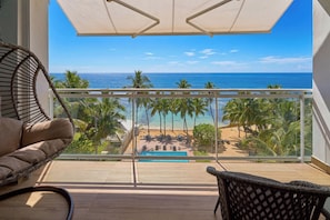 Ein Balkon mit Blick auf den Ozean, Palmen und einen Pool.