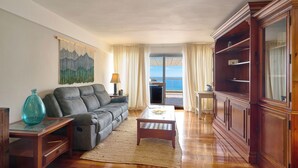 Una sala de estar con sofá, mesa de centro y aparador de madera.