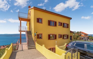 Ein gelbes Gebäude mit Treppe, Balkon und Meerblick.