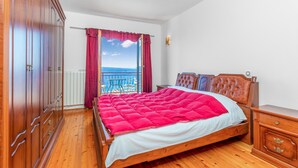 A bedroom with a wooden bed, a view of the sea, and a balcony. - Lovely apartment in Crikvenica (Crikvenica)