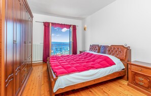 Ein Schlafzimmer mit einem Holzbett, Meerblick und einem Balkon.