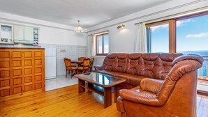 A living room with a brown leather sofa, a wooden coffee table, and a dining area with chairs and a table. - Lovely apartment in Crikvenica (Crikvenica)