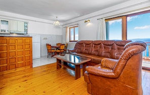 Ein Wohnzimmer mit braunem Ledersofa, einem Holztisch und einem Essbereich mit Stühlen und Tisch.