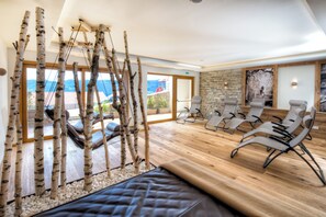 Een moderne spa met berkbomen, lounge fauteuils en uitzicht op de bergen.
