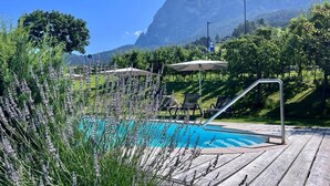 A pool area with a wooden deck, lounge chairs, and a mountain backdrop. - Hotel Gasthof Kircher (Fie allo Sciliar)