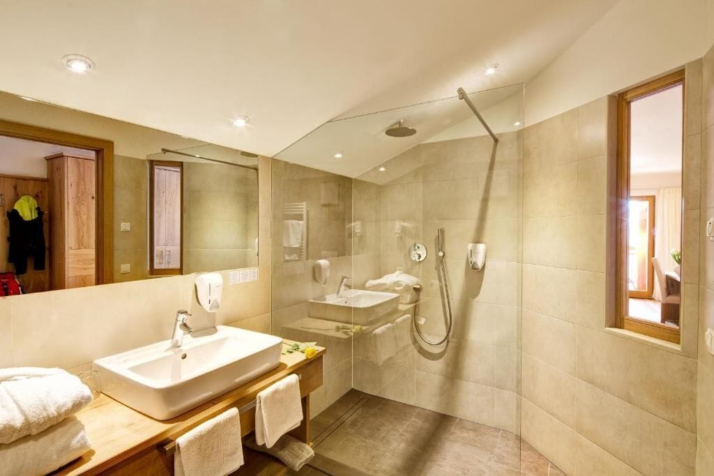 Un bagno moderno con un grande specchio, due lavandini, una doccia e un mobile bagno in legno.