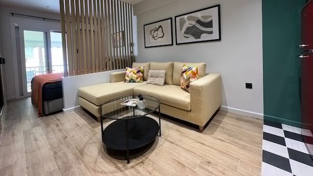 Una sala de estar moderna con un sofá, una mesa de centro de vidrio y vistas a través de un ventanal corredera.