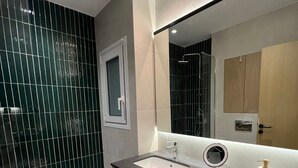 Un baño moderno con un espejo grande, dos lavamanos, una ducha y un inodoro.