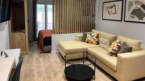 Una sala de estar moderna con un sofá, una mesa de centro de vidrio, un armario de madera y un televisor.