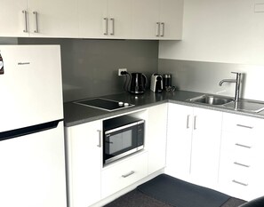Eine moderne Küche mit weißen Schränken, einer schwarzen Arbeitsplatte, einem eingebauten Backofen, einer Kaffeemaschine und einem Spülbecken.