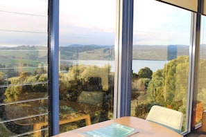 Ein Zimmer mit großen Fenstern und Blick auf einen See sowie die umliegende Landschaft.