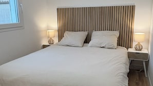 Ein Schlafzimmer mit einem Bett, zwei Nachttischen, einem Fenster und einem Holzkopfstück.
