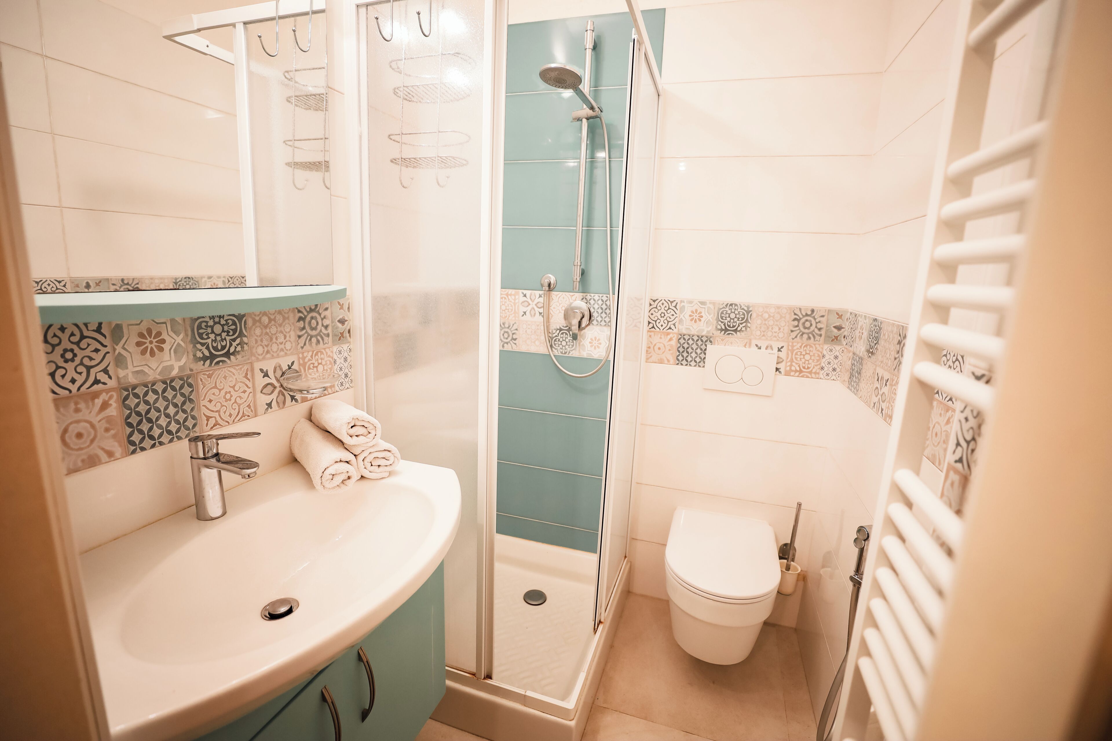 A bathroom with a sink, toilet, shower, and tiled walls.