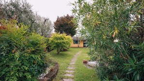 Un chemin de jardin qui mène à un bâtiment dont le toit est recouvert de tuiles.