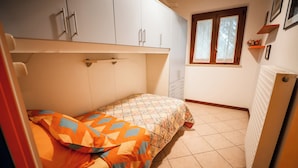 Une chambre à coucher avec un lit, une fenêtre, un radiateur et une armoire.