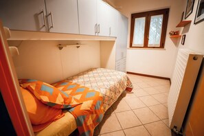 Un dormitorio con cama, ventana, radiador y armario.