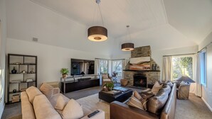 A modern living room with a fireplace, a sofa, a coffee table, and a television. - Mishika Retreat and Lodge (Wānaka)