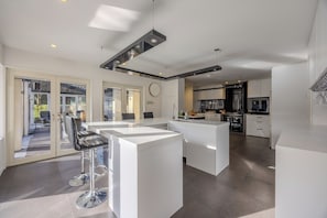 Una cocina moderna con armarios blancos, una isla central y un comedor con taburetes de bar.