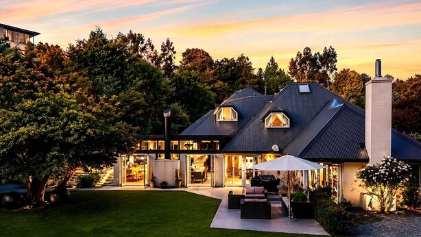 A modern house with a large lawn, a patio with outdoor furniture, and a garage. - Mishika Retreat and Lodge (Wānaka)
