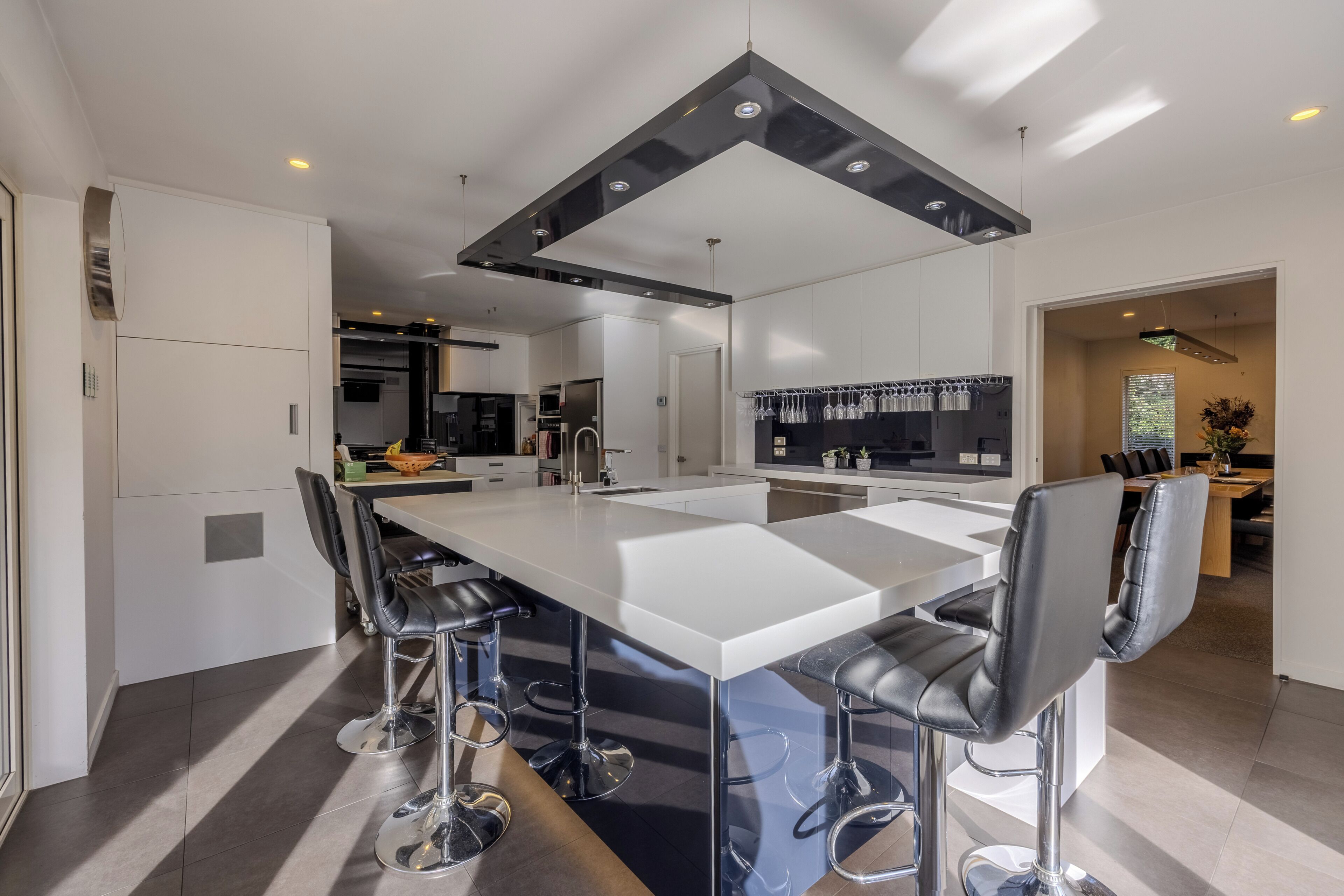 Una cocina moderna con una isla central, taburetes de bar y un comedor con mesa y sillas.