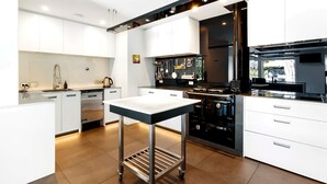 A modern kitchen with white cabinetry, stainless steel appliances, and a central island. - Mishika Retreat and Lodge (Wānaka)