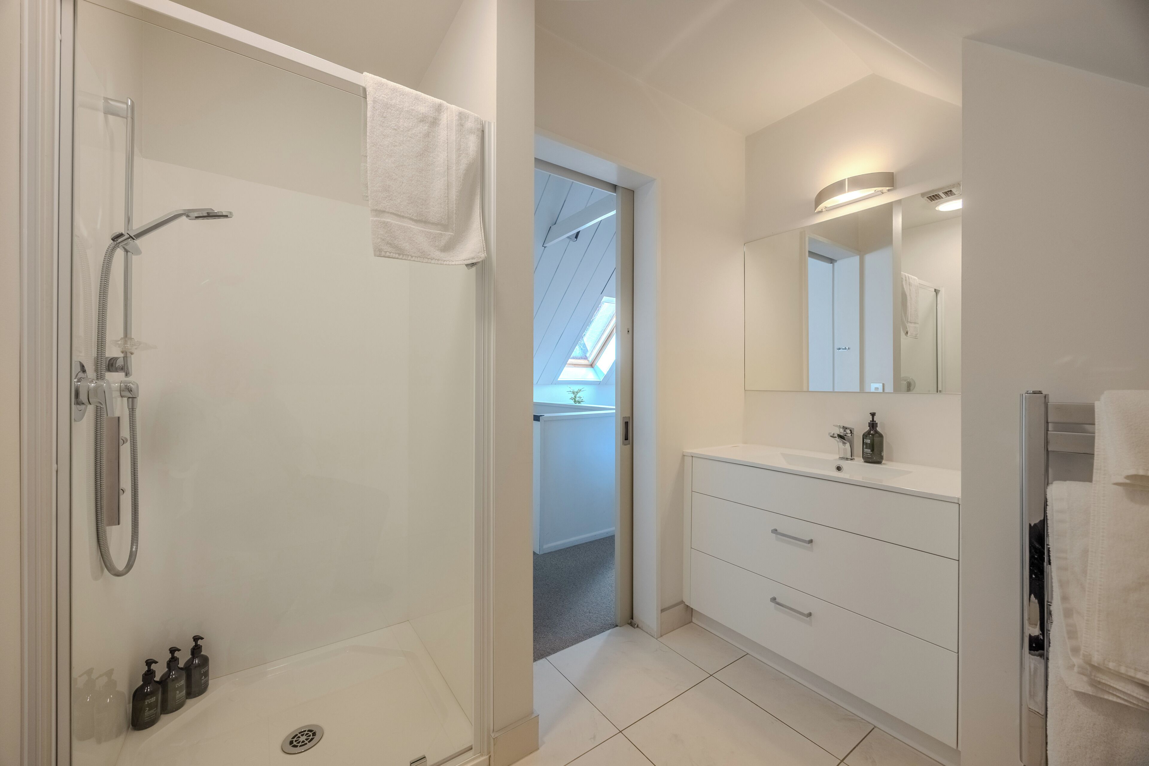 A modern bathroom with a shower, toilet, and sink.