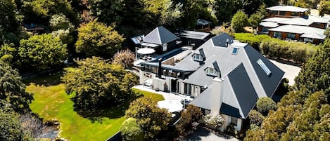A modern house with a large driveway, surrounded by dense greenery and trees.